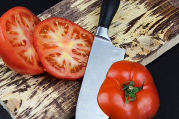 High Angle View Of Tomato Slices With Knife On Cutting Board On Dark Background. Wooden Cutting...