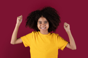 Positive african american girl raising fists up and smiling