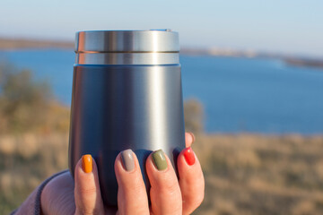 A travel mug in the hands of a women.