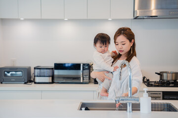 赤ちゃんを抱っこしながら家事をするお母さん © maroke