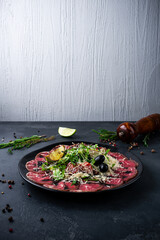 Beef carpaccio: beef tenderloin, romaine lettuce, sun-dried tomatoes, parmesan cheese on a table.