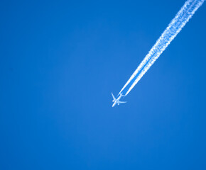 high altitude twin engine contrails (jet airplane vapour trails) across a deep blue clear sky