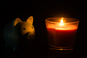 Piggy bank with candles against dark background.