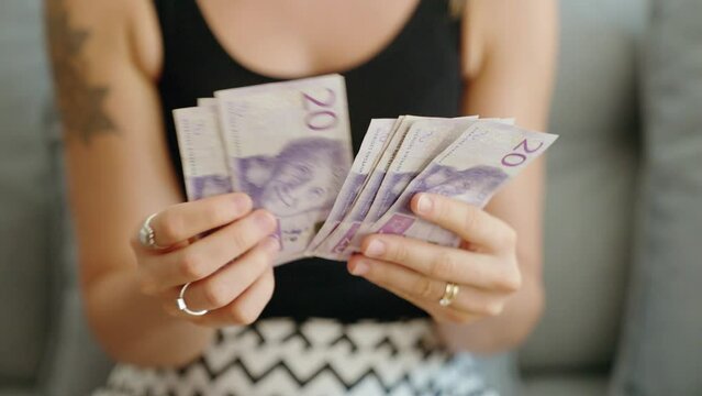 Young woman counting sweden 20 kronor banknotes at home