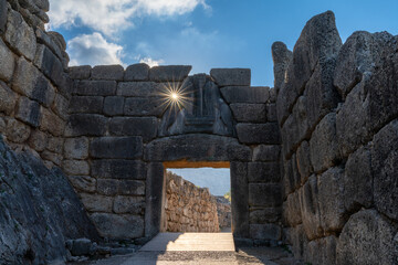 view of the Lion Gate entrance portal at the ancient citadel of Mycenae with a morning sunburst