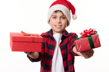 Selective focus on happy Christmas or New Year's gifts in hands of blurred pretten boy in Santa hat, smiling looking at camera, isolated on white background. Time to open presents. Winter holidays