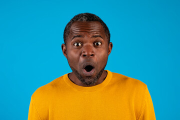 Shocked black man looking at camera, isolated on blue