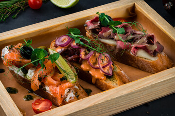 Assorted bruschetta with salmon, beef cut, sun-dried tomatoes, onion, mushrooms, cream cheese and baguette, closeup.