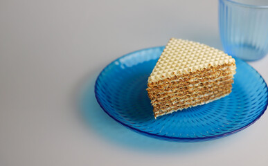 sweet waffle triangular piece of cake soaked in boiled condensed milk on a blue kitchen round plate. for flyers banners signage labels