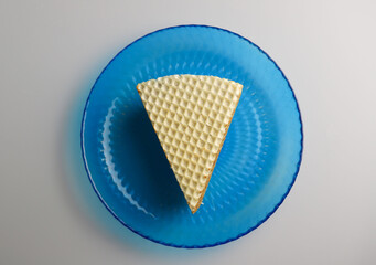 sweet waffle triangular piece of cake soaked in boiled condensed milk on a blue kitchen round plate. for flyers banners signage labels
