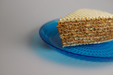 sweet waffle triangular piece of cake soaked in boiled condensed milk on a blue kitchen round plate. for flyers banners signage labels