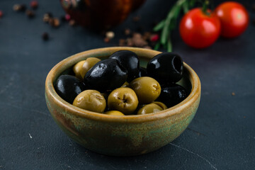 Olives and black olives in a bowl on a dark background. - obrazy, fototapety, plakaty