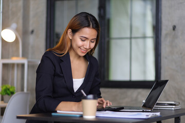 Businesswoman accountant in an accounting firm working with financial audits and budgeting using a calculator and laptop.