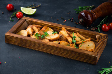 Baked potato wedges with salt on a wooden board.