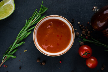 Tomato ketchup sauce in a bowl with rosemary, tomatoes, lime and spices.