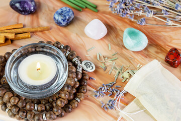 Self-care, healing composition with rosary beads, aroma sticks, chakra stones, sandalwood sticks and candle on a pink marble podium. Concept of relaxing at home, energy healing, meditation and me time