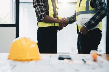 Architect and engineer construction workers shaking hands while working for teamwork and cooperation concept after finish an agreement in the office construction site, success collaboration concept