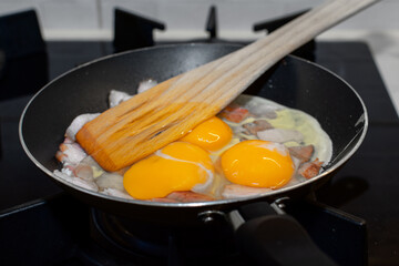 Scrambled eggs with bacon in a pan.