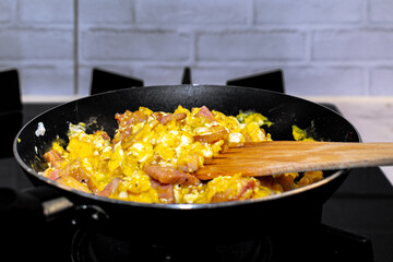 Scrambled eggs with bacon in a pan.