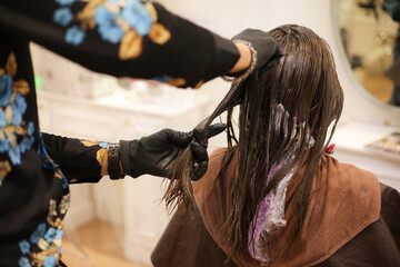 女性の髪に薬剤を塗布する男性美容師