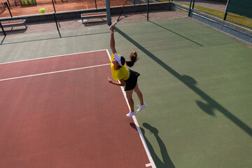 Professional equipped female tennis player beating hard the tennis ball with racquet. Top view.