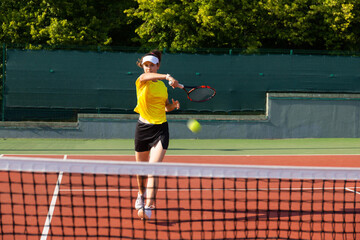 Obraz premium Professional equipped female tennis player beating hard the tennis ball with racquet.
