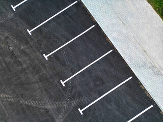 Fototapeta premium Top aerial view of empty spaces in parking lot. Parking spaces for cars. Parking on the side of the road in the city.