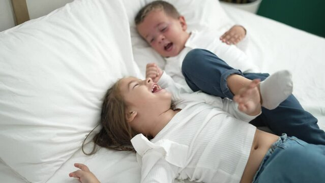 Adorable girl and boy laying on bed screaming and kicking at bedroom