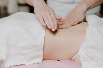 Fototapeta na wymiar Close-up of a female masseur massaging a woman's abdomen in a spa. Side view
