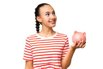 Young Arab woman holding a piggybank over isolated background looking up while smiling