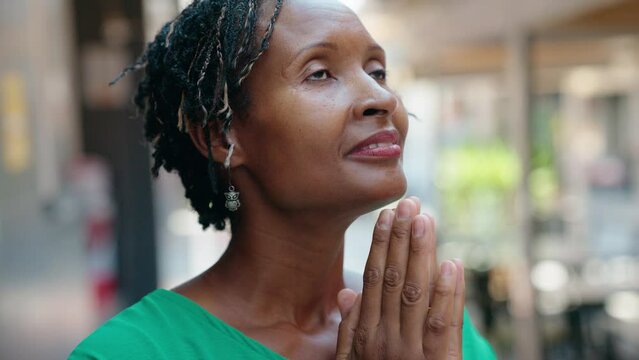 Middle age african american woman smiling confident praying at street