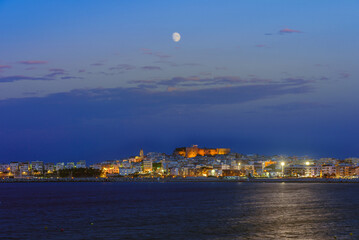 Vieste, Italy. View of the town of Vieste after sunset at dusk with the moon high in the sky....