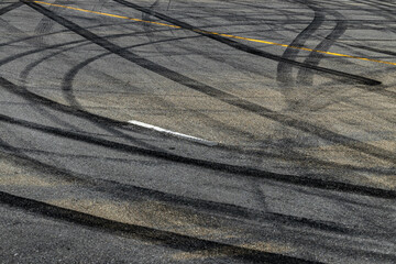 Tire track mark on asphalt tarmac road race track texture and background, Abstract background black tire tracks skid on asphalt road in racing circuit, Tire mark skid mark on asphalt road. © Darunrat
