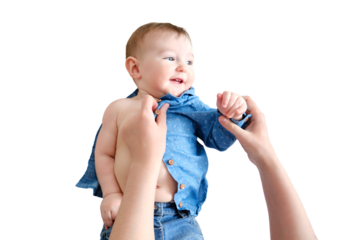 A mother woman wears a blue shirt to a baby boy, isolated on a white background. Mom dresses a happy child in clothes. Kid nine months old