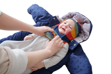 A mother woman puts on a warm hat for a baby boy, isolated on a white background. Mom dresses a happy child in winter clothes. Kid nine months old