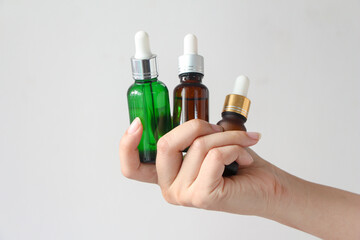 Woman hands holding facial essential oil or serum packaging on white background. Beauty cosmetic product for skincare concept.