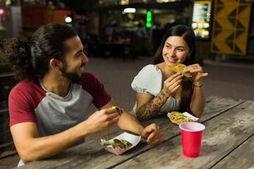 Attractive couple eating mexican tacos from the food truck