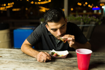 Hispanic man eating delicious tacos and street food
