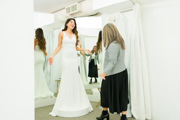 Cheerful woman doing a dress reveal of her wedding gown with her mother