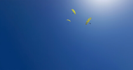Israel, three skydivers in the blue sky in sunlight. Taken on a phone. selective focus