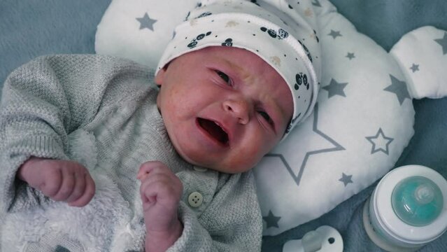 Small newborn baby girl crying lying on her back