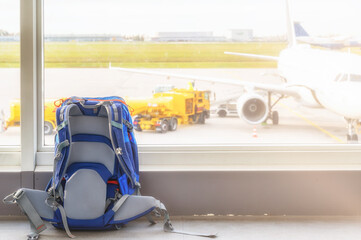 Handgepäck im Terminal eines Flughafens mit Rollfeld und Flugzeug im Hintergrund
