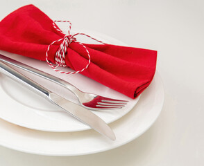 Holiday table setting. Silver Cutlery and red cloth napkin on white plate, close up