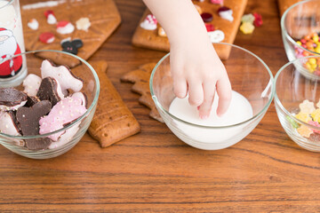  Child interacting with gingerbread houses, cookies and candy. The photo captures a joyful, festive scene with holiday treats ready for consumption. 