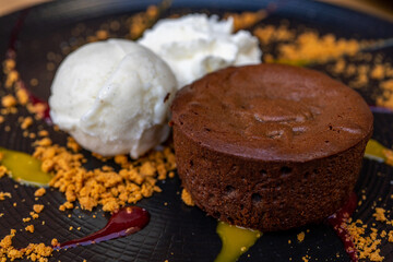 Plate of delicious warm dessert chocolate cake Fondant served with ice-cream balls. Lava cake on a decorated plate.