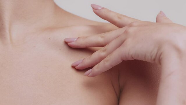 Youth and beauty. Close up of woman caressing her decollete with hand, demonstrating perfect smooth skin, tracking shot