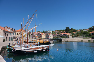 Sailing boats on marina in Hvar town harbor. Harbour in Hvar island, Croatia, Europe on a bright sunny day in Summer. Blue sky and calm sea. Hvar town with traditional Dalmatian architecture.
