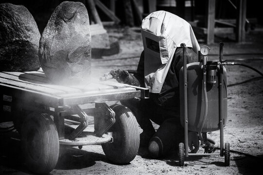 Cleaning Granite Boulder Rock Surface With Sand Blasting Method. Browing Sand With High Air Pressure