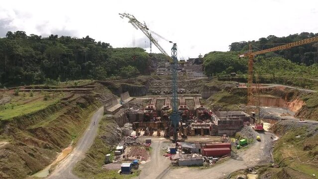 Aerial view. Construction of a hydroelectric power plant. Construction cranes on an industrial site. Flying over an industrial zone in Africa. Equatorial Guinea, Africa.