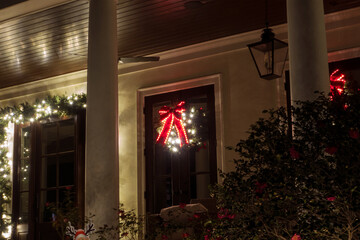 Beautiful, illuminated Christmas wreath and lights on a front door with Tuscan columns in the foreground